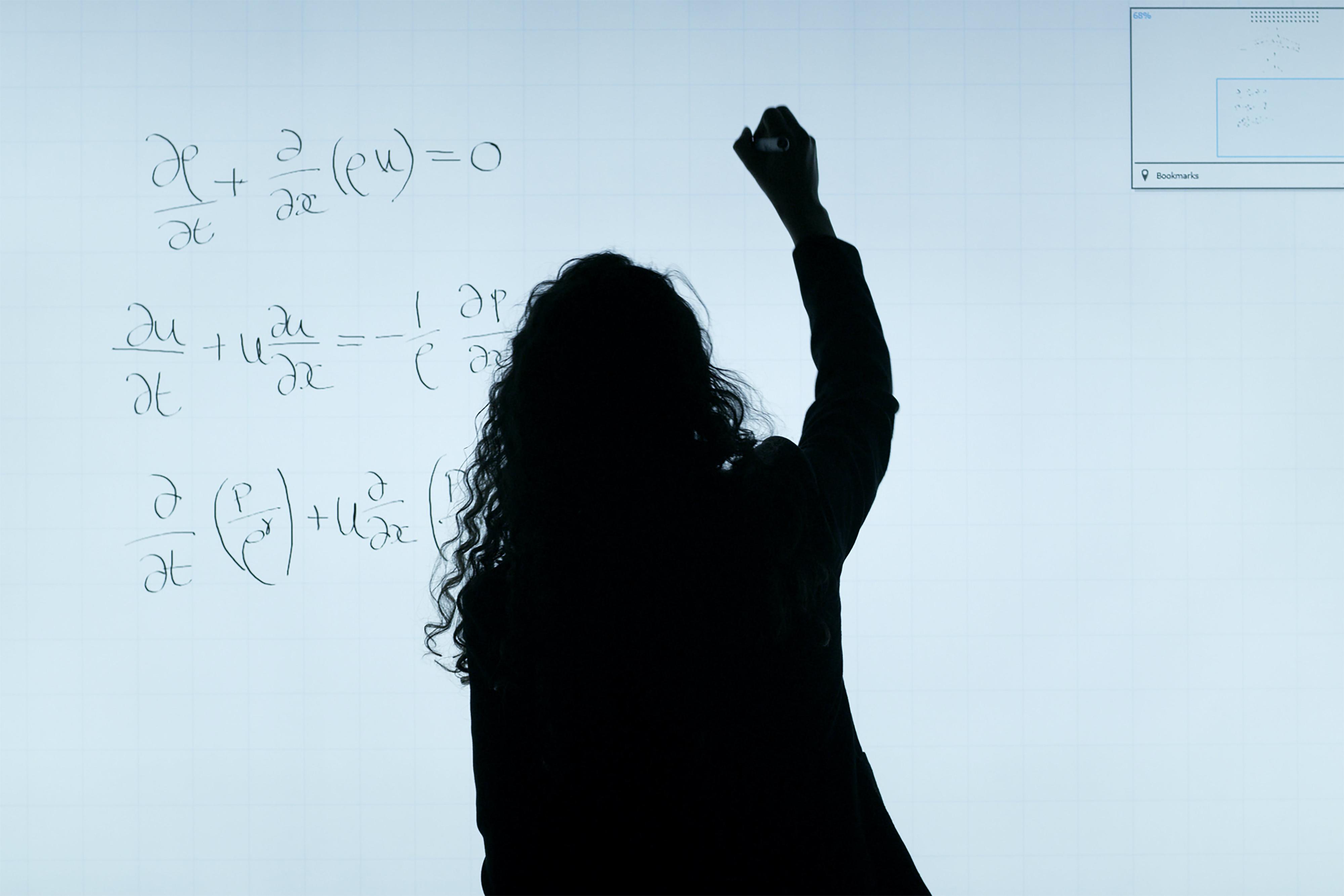 A woman writing on a whiteboard.